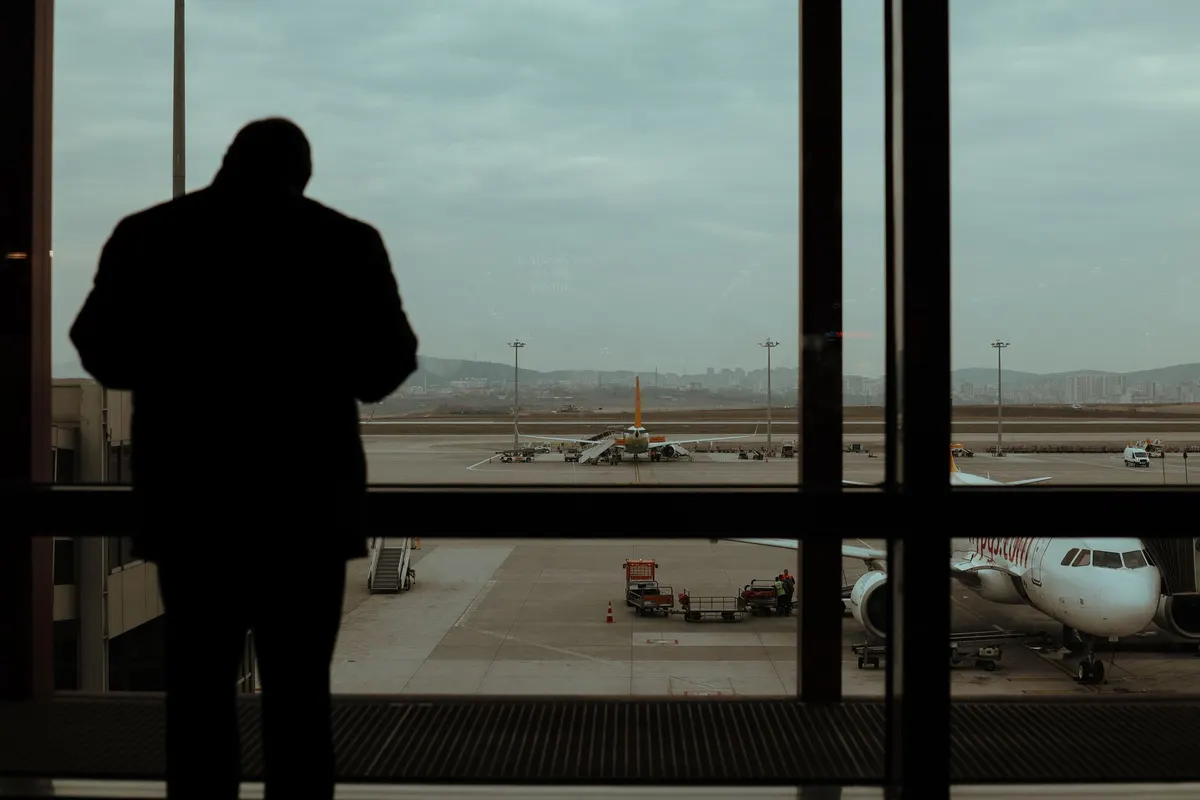Silueta de una persona observando aviones en la pista desde el aeropuerto