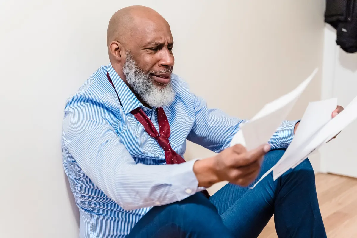 Hombre leyendo documentos con expresión de preocupación