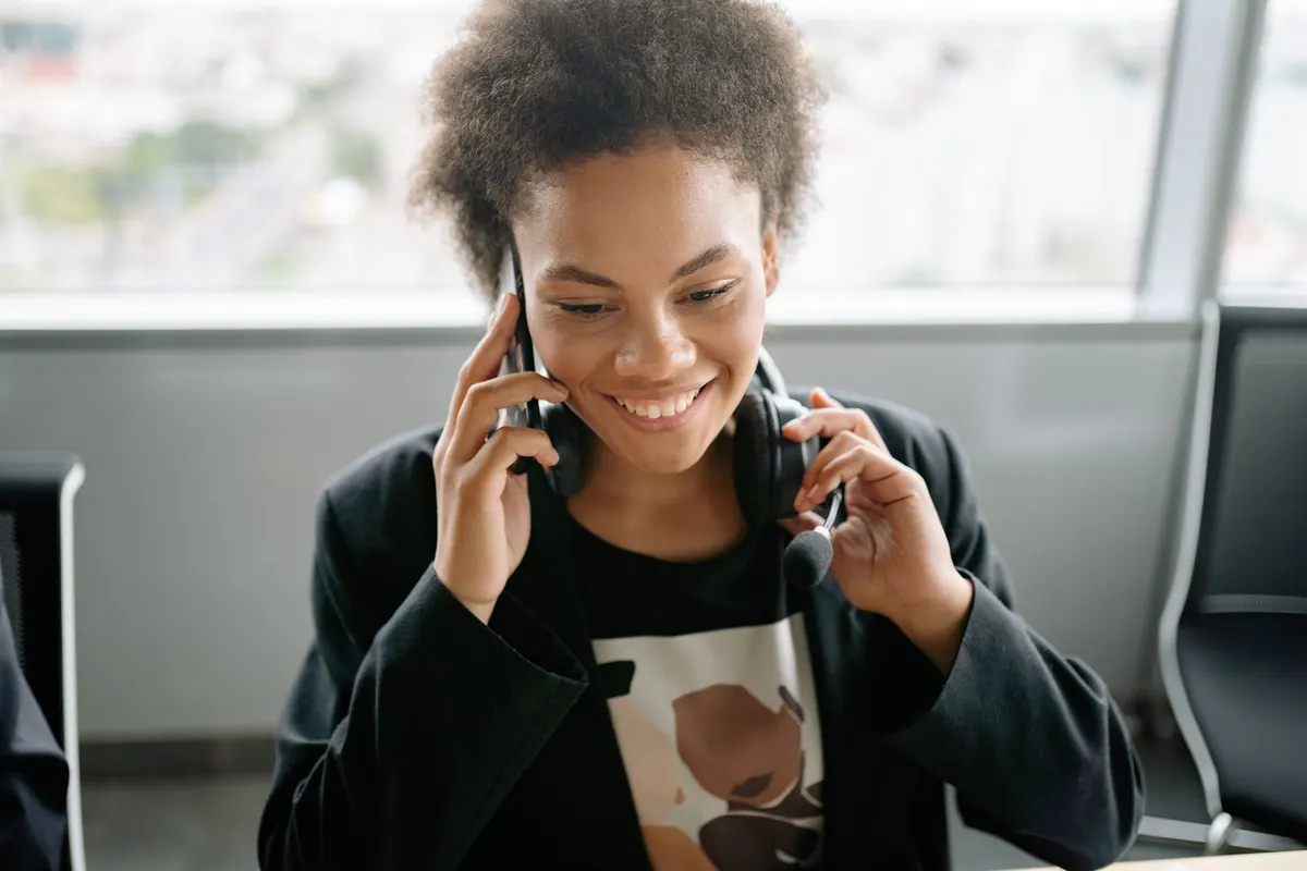 Mujer sonriente hablando por teléfono con auriculares de atención al cliente